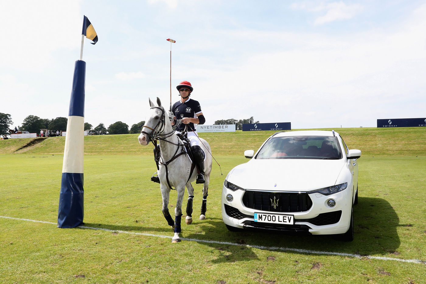 Boy plays polo with a white Maserati Levante beside him