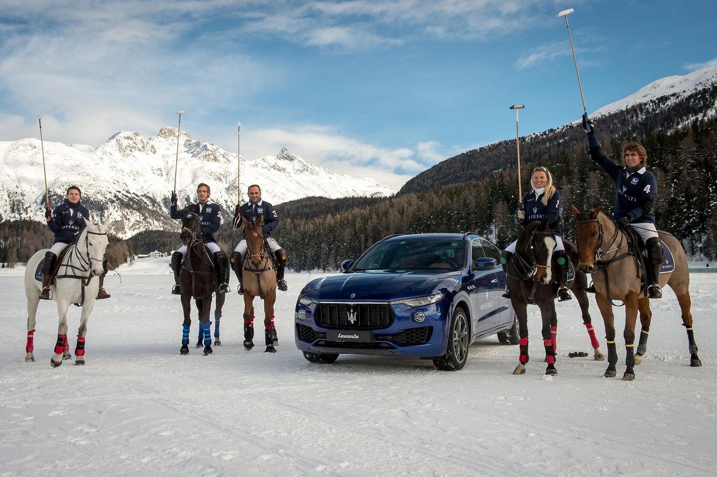 Polo players with raised clubs and Maserati Levante in the center