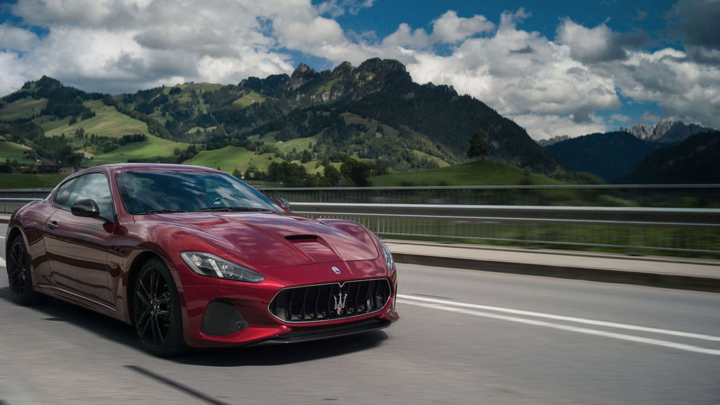Maserati GT on road in front of mountains