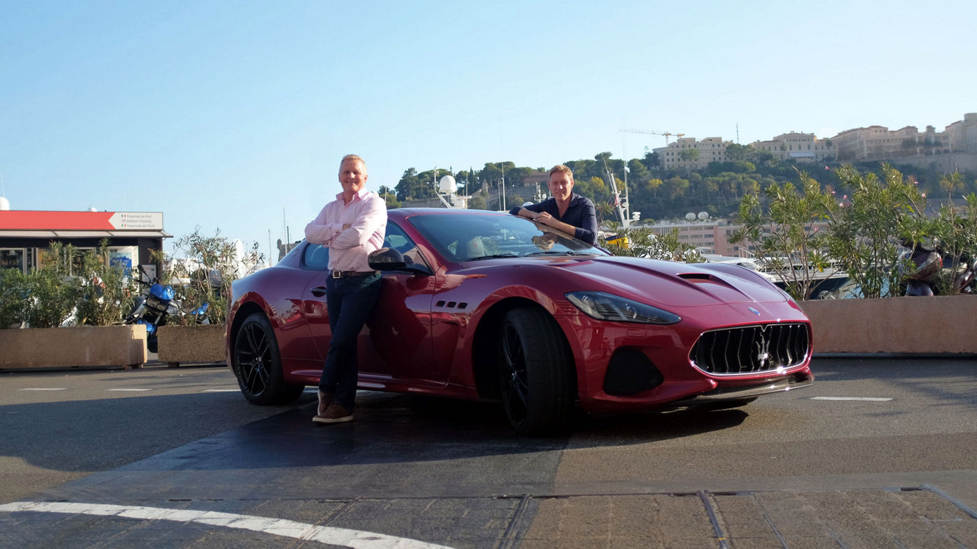 Johnny Herbert and other man leaning on Red Maserati GranTurismo