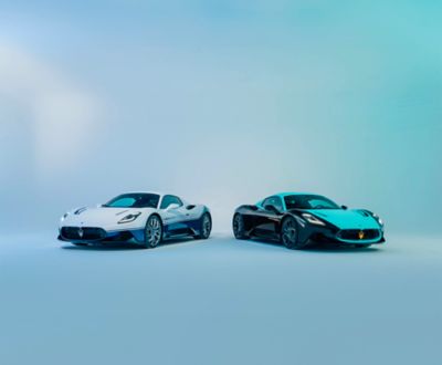 Maserati MC20 Icona with white-blue livery and MC20 Legend with black-mint livery side by side on abstract blue scenery
