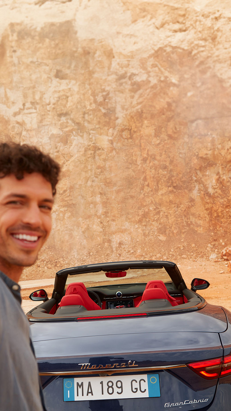 Un jeune homme prend un selfie à côté de la nouvelle Maserati Grancabrio 2024 lors d'un voyage dans le sud de l'Italie.