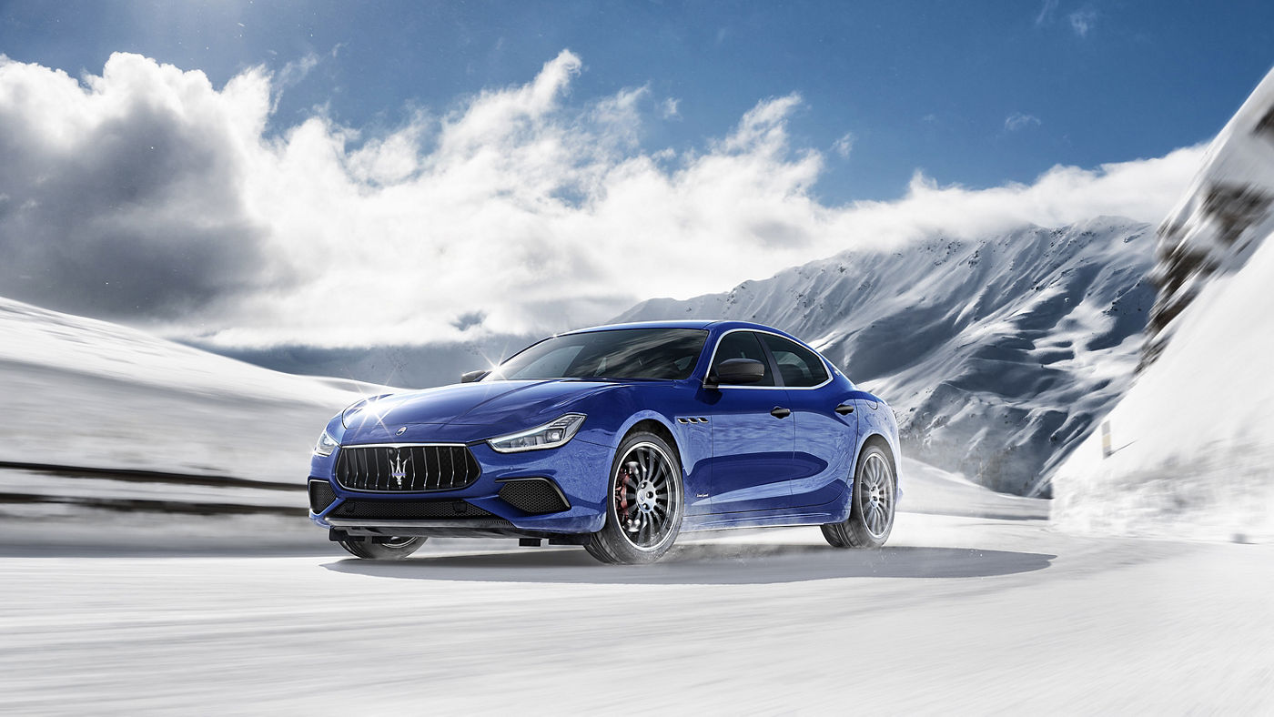 A blue Maserati Ghibli running on a snowy road