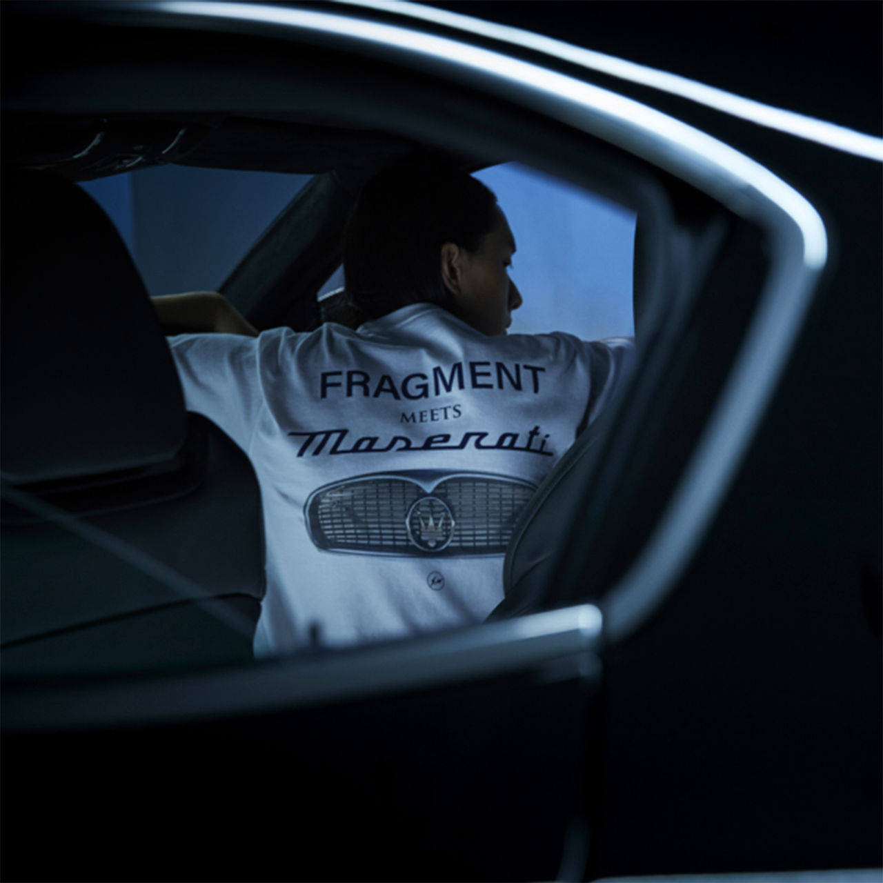 "Fragment Meets Maserati" written on a t-shirt of a man sitting inside a Maserati vehicle