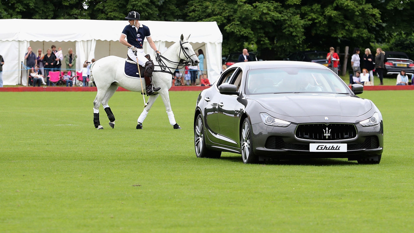 Maserati Ghibli sul campo da polo con giocatore dietro 
