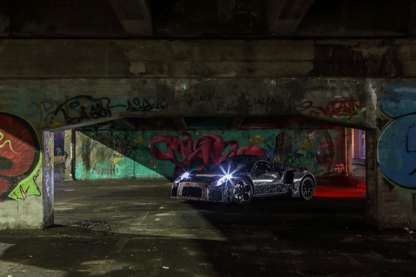 nuovo prototipo auto Maserati vista frontale con sfondo graffiti e fari accesi