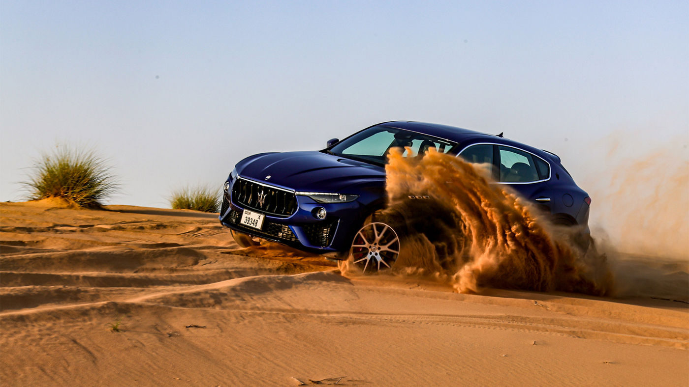 Maserati Grecale bleu nuit roulant dans le désert aux Emirats Arabes Unis