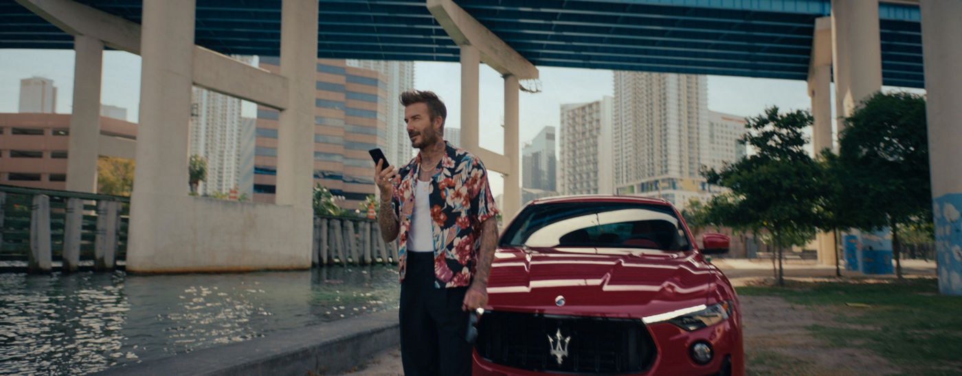 David Beckham con un móvil delante del SUV Maserati Levante Trofeo rojo