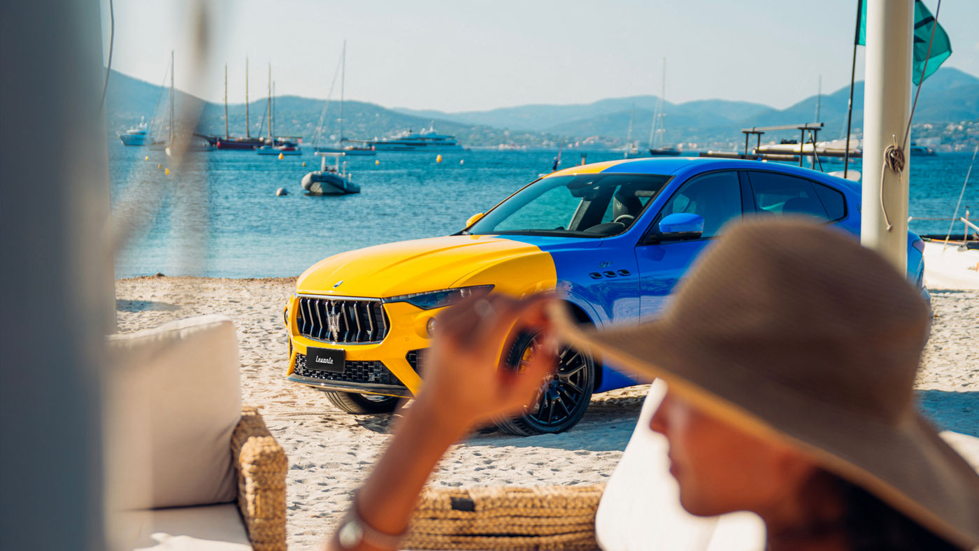 Yellow and blue Maserati Levante Hybrid on the beach of Saint Tropez