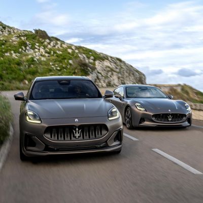 A Grecale Folgore and a Granturismo Folgore shot head-on travel along a coastal road side by side