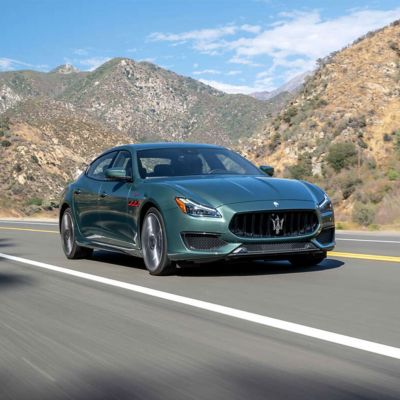 A dark green Maserati Quattroporte parades along a mountain road