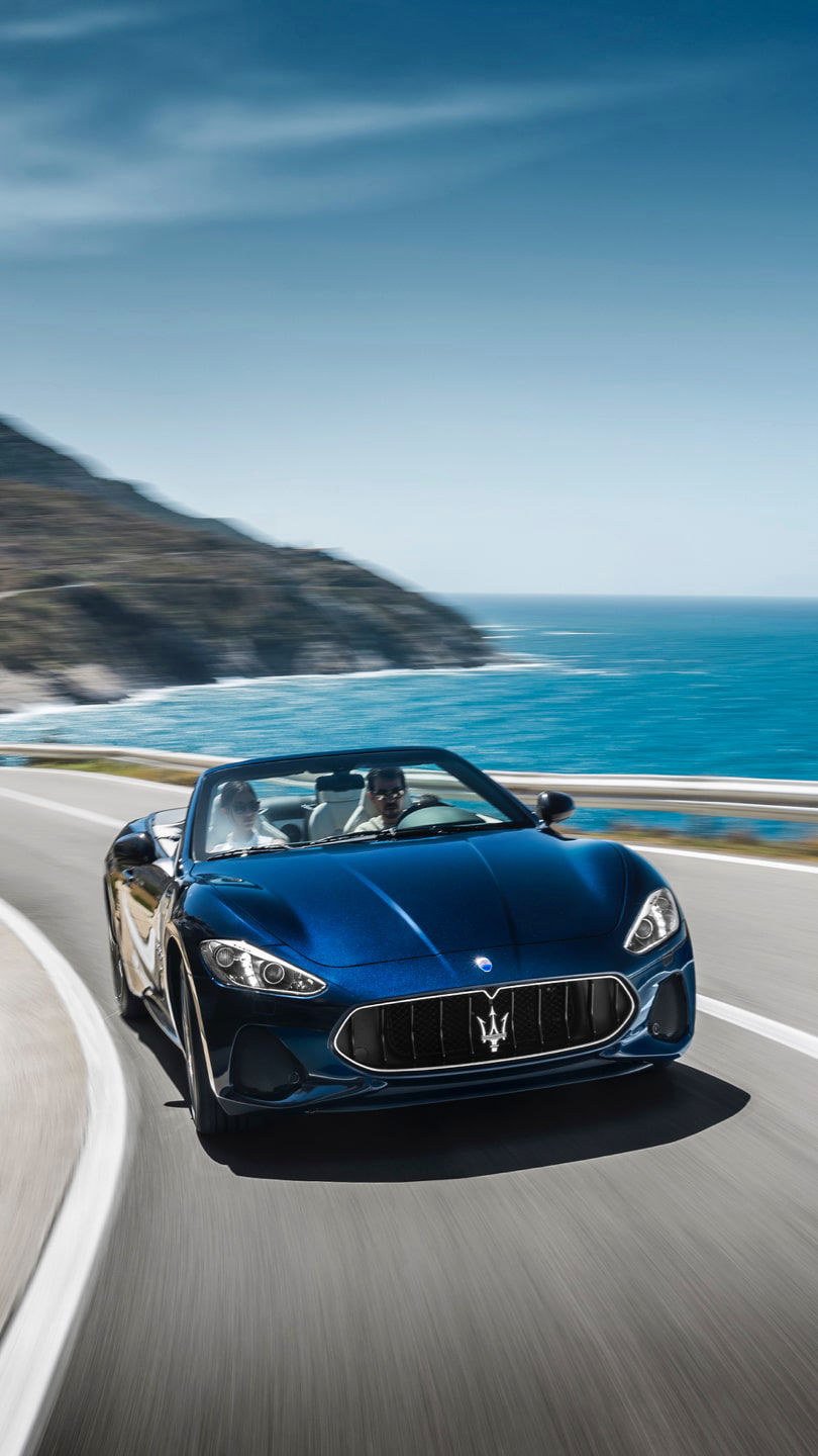 Original Zubehör: Maserati GranCabrio in Blau fährt auf einer Straße am Meer