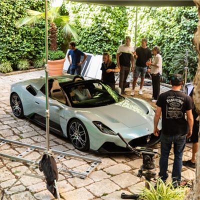A Maserati MC20 Cielo in an outdoor location in Puglia, surrounded by a production team during a photo session.