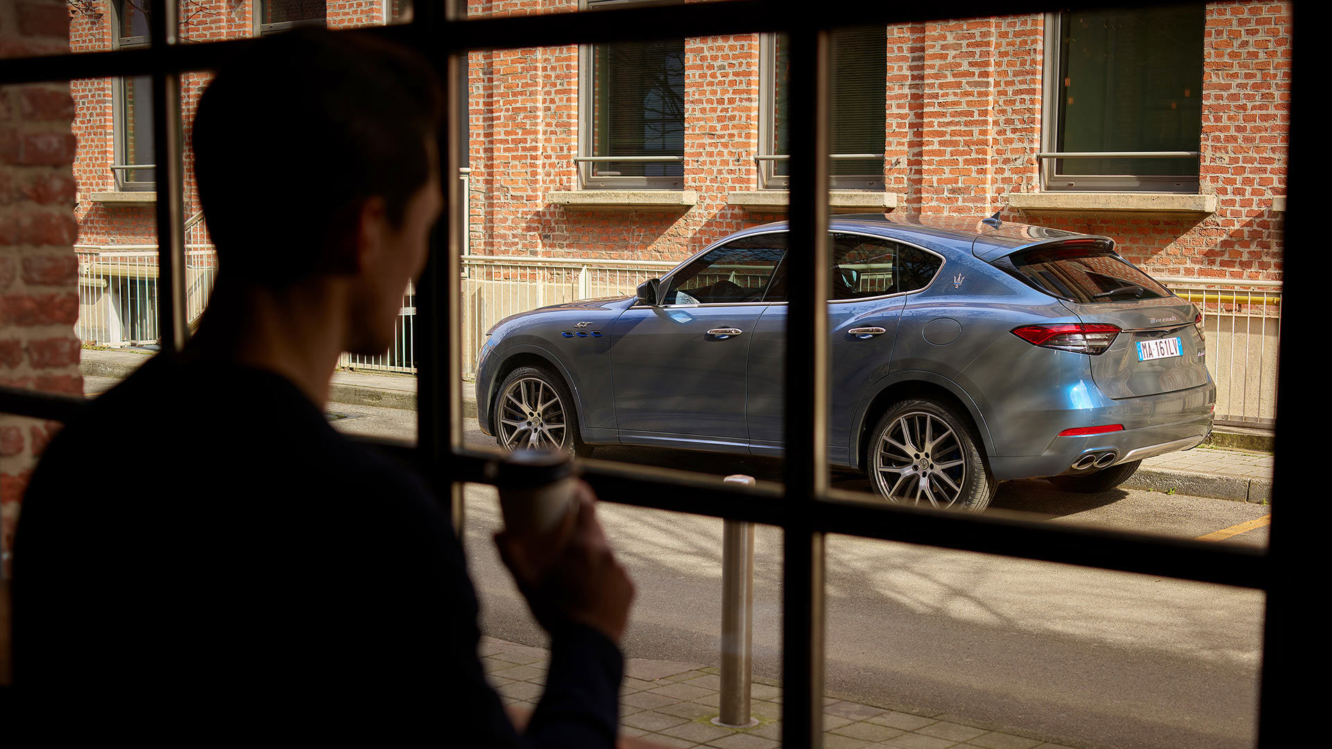 Hombre que mira por la ventana el SUV Maserati Levante GT