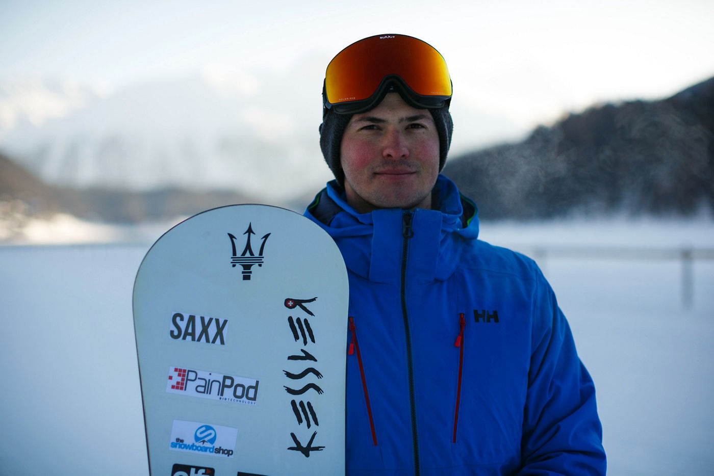 Jamie Barrow con tabla de snowboard con logo Maserati en la nieve