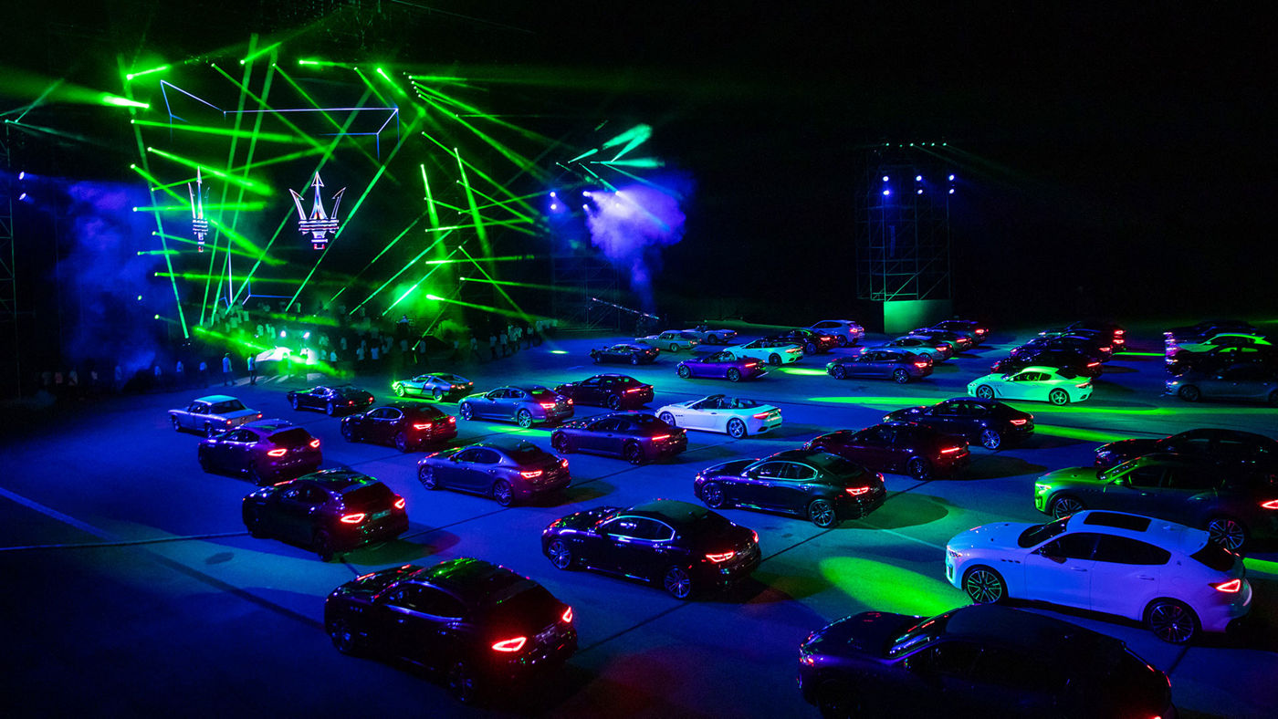 Modelos Maserati cerca de un escenario iluminado por luces verdes