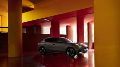 A gray Maserati Grecale Folgore coming out of a modern garage with red and yellow walls