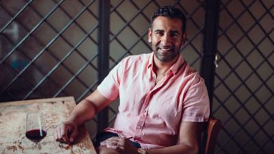 Rajvinder Bains seated at the table with a glass of red wine placed on the table