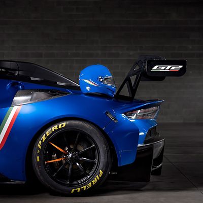 Side view of a blue Maserati GT2 race car, with a helmet resting on the roof, emphasizing Italian craftsmanship and racing DNA.