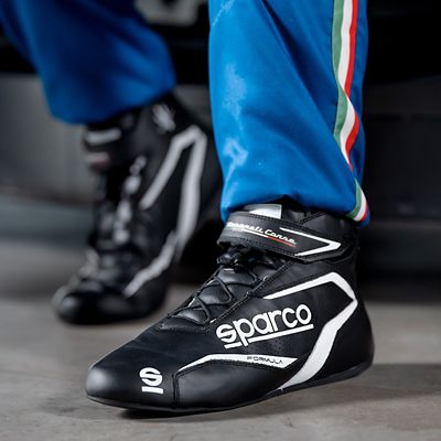 Close-up of Sparco racing shoes worn by a driver in a blue Maserati racing suit, highlighting comfort and performance on the track.